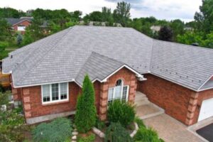 Light gray shingle roof installed on a large, brick home