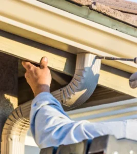 man using drill to install a gutter downspout